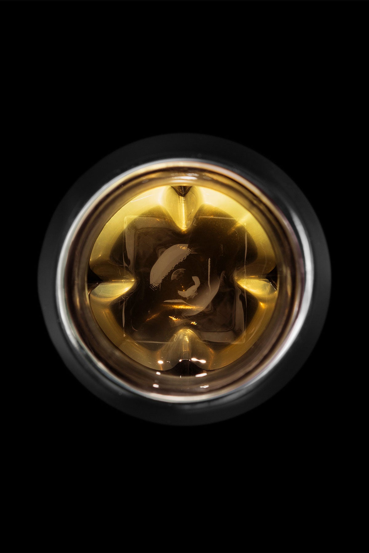 The Vaild black edition of the Norlan Whisky Glass viewed directly from above with a light golden whiskey inside and the inner protrusions of the glass highlighted to show this unique attribute of the design by Sruli Recht.