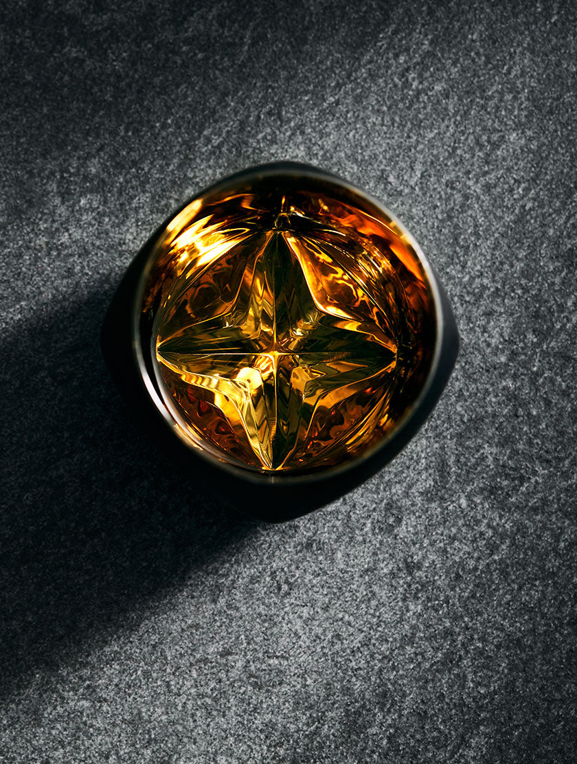 Black edition of the Rauk Heavy Tumbler viewed from above with a brilliant glow of whisky inside.