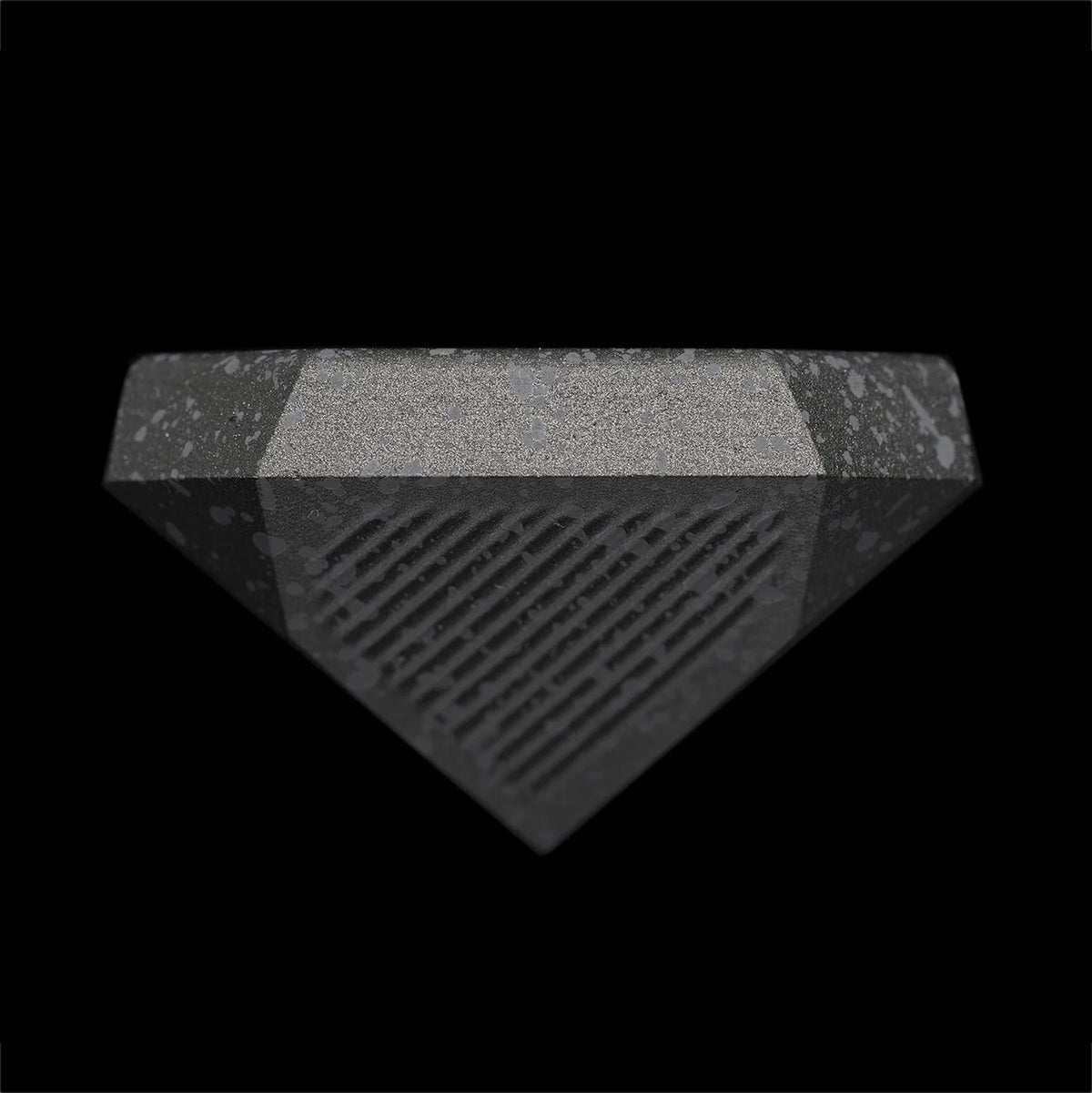 A detailed view of the Nyht Whisky Decanter lid right-side up. The close-up image highlights the detail of the precision machined aluminum list and the splatter paint finish. From this view, the lid takes on the form of  an upside-down metal pyramid with facets on the corner that mimic the details in the base of the glasses.