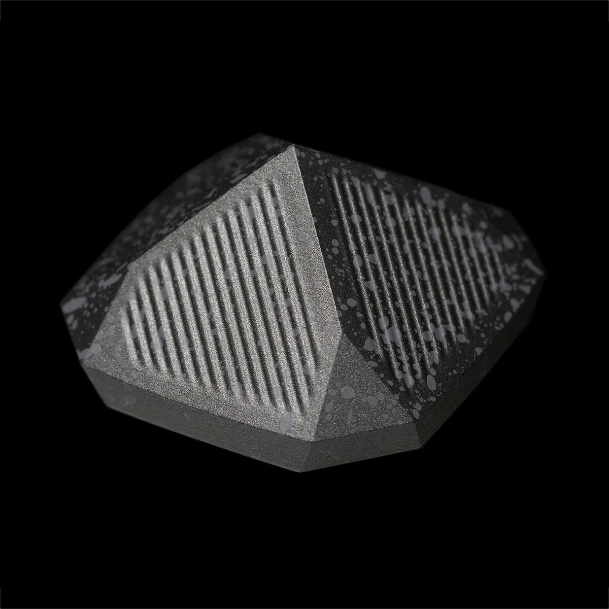 A detailed upside view of the Nyht Whisky Decanter lid with the bottom of the lid in view. The close-up image highlights the detail of the precision machined aluminum list and the splatter paint finish. From this view, the lid takes on the form of  a metal pyramid with facets on the corner that mimic the details in the base of the glasses.