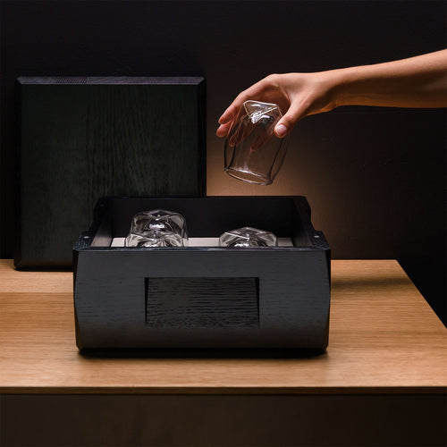 A woman's hand retrieving a Norlan Whisky Glass from the decorative wooden Kist Storage Case