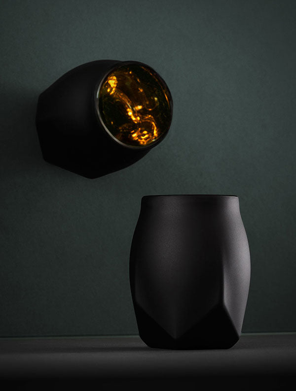 The Vaild black edition of the Norlan Whisky Glass viewed from the side with a mirror placed behind and at an angle to show the glowing liquid within our cool whisky glass.