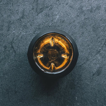 A bird's eye view of the black edition of the Norlan Whisky Glass, highlighting the inner protrusions with whisky glowing inside. 