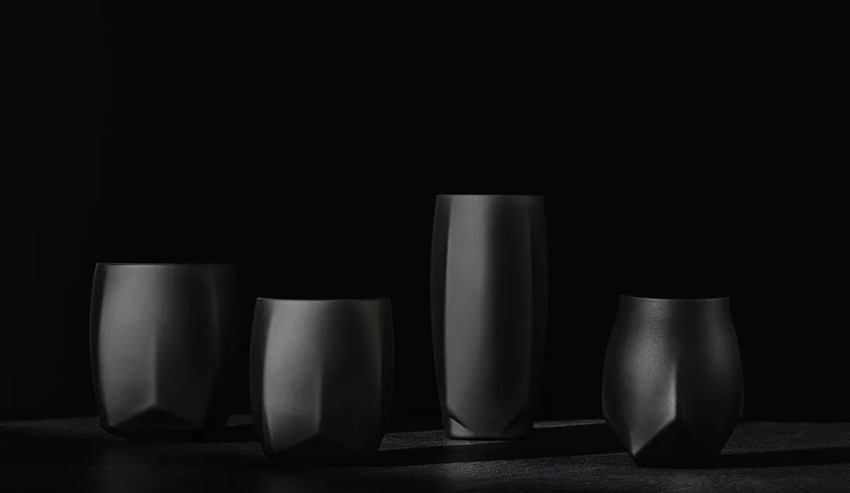 An image showing a lineup of the VAILD (Black) whiskey glasses in the Norlan collection. From left to right and all in the VAILD (Black) Finish:  1. The Rauk Heavy Tumbler, 350 mL. 2. The Rauk Heavy Tumbler, 250 mL, 3. The Vawe Highball Glass, 4. The Norlan Whisky Glass