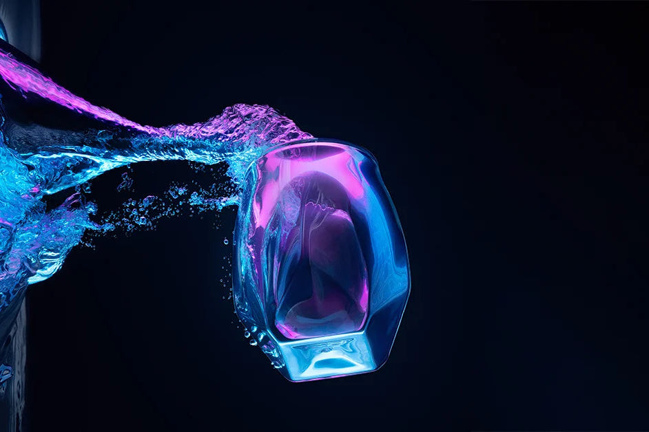 Norlan Whisky Glass mid-splash against a dark background, showcasing its faceted design and modern aesthetic.