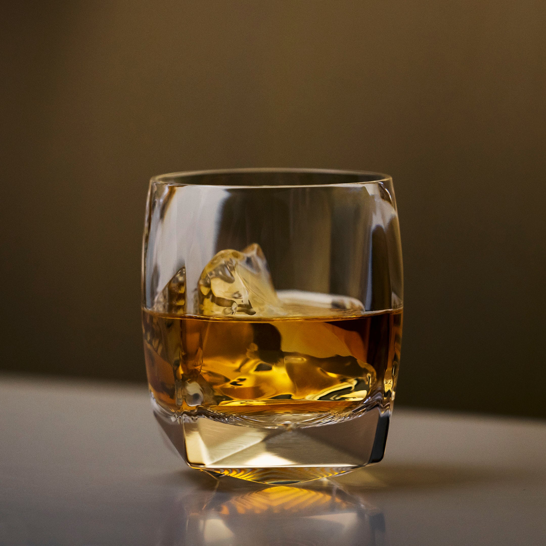 A heavy crystal tumbler filled with whiskey and ice