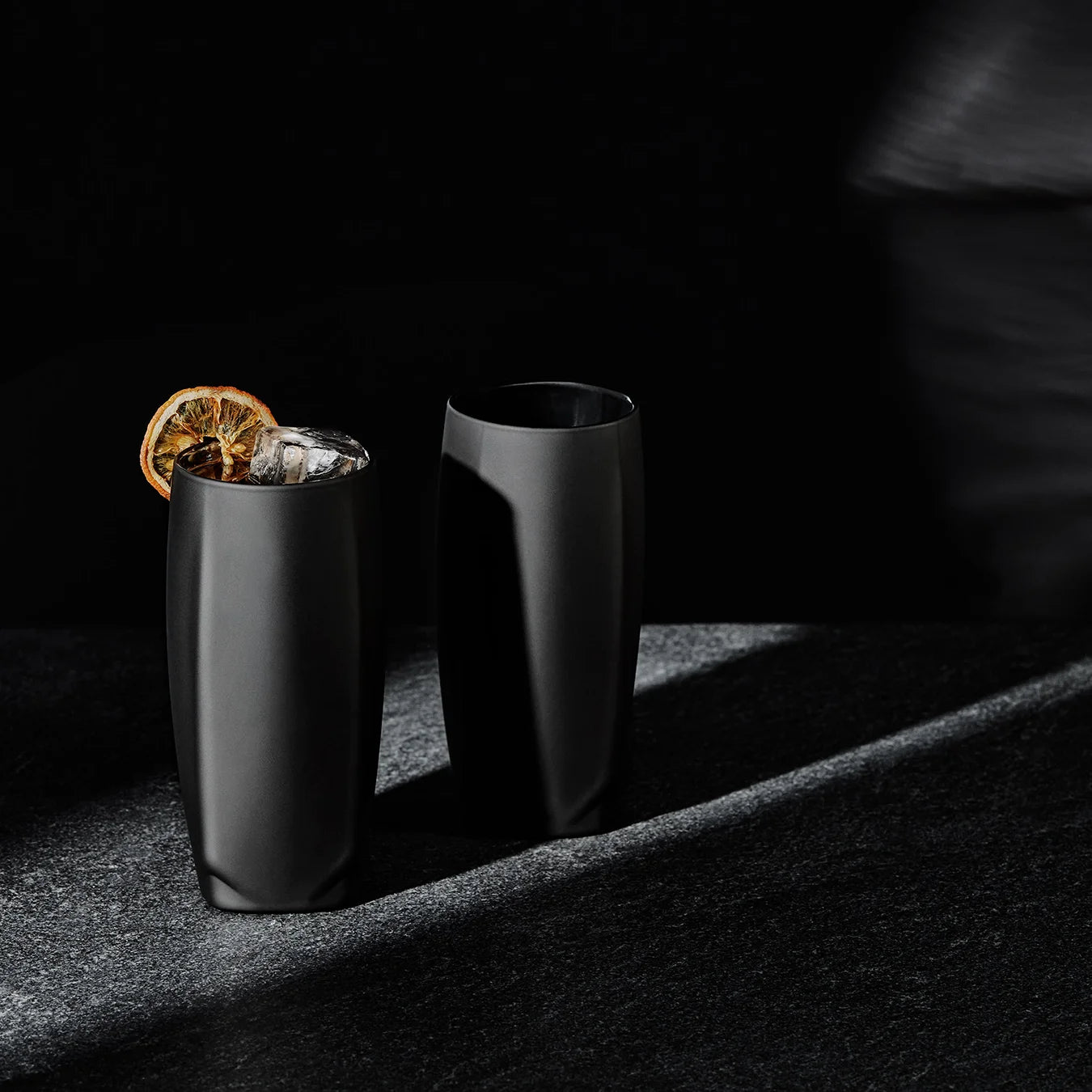 Vawe Highball Glass in matte black exterior with mirrored interior, elevated whiskey drinking with a collins cube and orange wheel